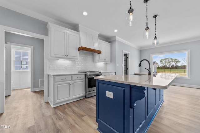 2379 Heartland Rd, Battleboro, NC 27809 - kitchen with stainless steel stove, custom exhaust hood, light wood-style flooring, white cabinets, and a center island with sink