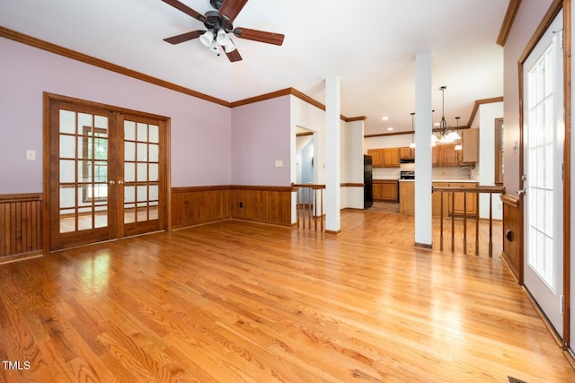 5020 Celbridge Pl, Raleigh, NC 27613 - unfurnished living room featuring french doors, light wood-style floors, plenty of natural light, ornamental molding, and a wainscoted wall