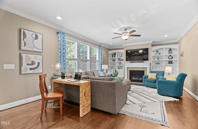 2712 Lake Waccamaw Trl, Apex, NC 27502 - living area with crown molding, wood finished floors, a ceiling fan, a glass covered fireplace, and recessed lighting