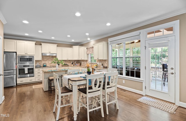2712 Lake Waccamaw Trl, Apex, NC 27502 - kitchen with appliances with stainless steel finishes, ornamental molding, a kitchen island, backsplash, and white cabinetry
