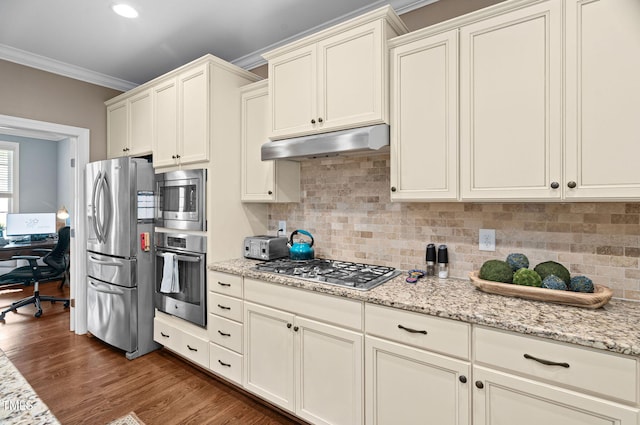 2712 Lake Waccamaw Trl, Apex, NC 27502 - kitchen featuring stainless steel appliances, under cabinet range hood, ornamental molding, backsplash, and dark wood-style floors
