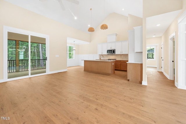 140 Purslane Dr, Franklinton, NC 27525 - kitchen with stainless steel microwave, open floor plan, light wood-type flooring, a center island with sink, and high vaulted ceiling