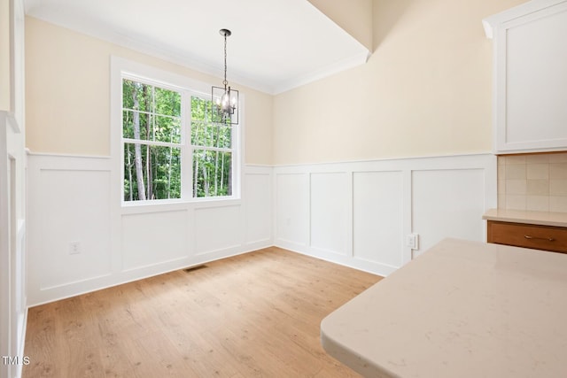 140 Purslane Dr, Franklinton, NC 27525 - unfurnished dining area featuring a decorative wall, a chandelier, a wainscoted wall, light wood-style flooring, and crown molding