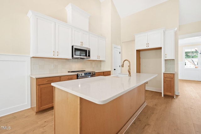 140 Purslane Dr, Franklinton, NC 27525 - kitchen featuring stainless steel appliances, light wood-type flooring, decorative backsplash, white cabinets, and a towering ceiling
