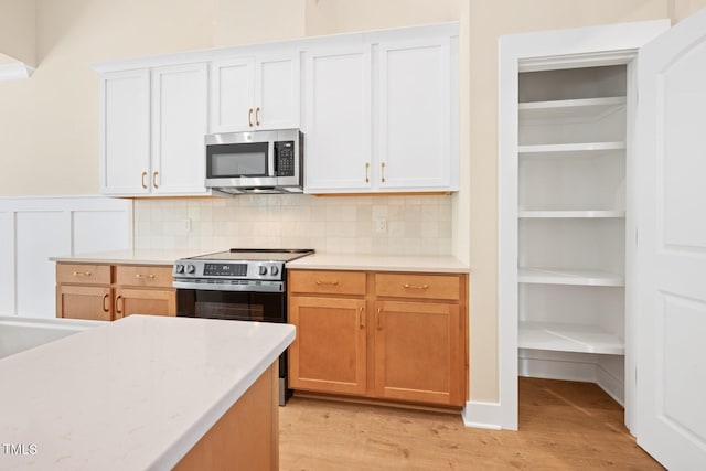 140 Purslane Dr, Franklinton, NC 27525 - kitchen with stainless steel appliances, light countertops, light wood-style flooring, decorative backsplash, and a wainscoted wall