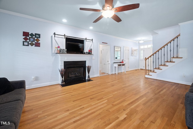 1824 Ferrell Meadows Dr, Zebulon, NC 27597 - living room with a ceiling fan, stairway, crown molding, wood finished floors, and a fireplace with flush hearth
