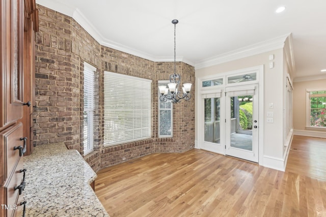 528 Bankhead Dr, Cary, NC 27519 - unfurnished dining area featuring crown molding, a chandelier, light wood-style floors, and brick wall