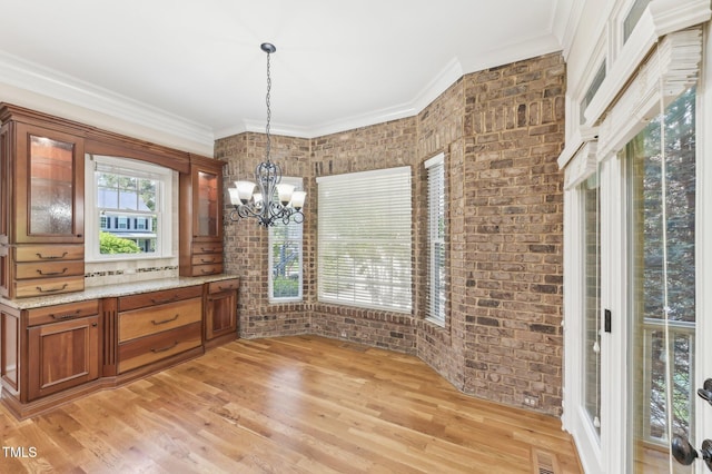 528 Bankhead Dr, Cary, NC 27519 - unfurnished dining area with a chandelier, brick wall, light wood-style floors, and crown molding