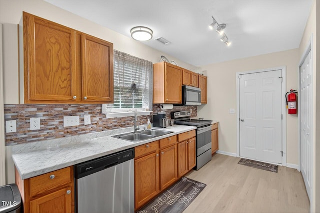 5 Ocean Ct, Durham, NC 27704 - kitchen featuring stainless steel appliances, light wood-type flooring, decorative backsplash, brown cabinetry, and track lighting