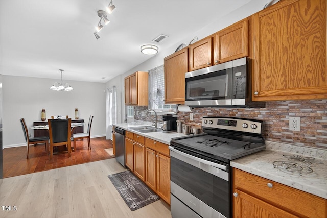 5 Ocean Ct, Durham, NC 27704 - kitchen featuring appliances with stainless steel finishes, light countertops, a chandelier, and decorative backsplash