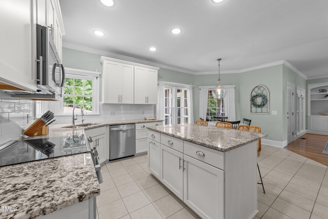 7908 Mayapple Pl, Raleigh, NC 27613 - kitchen featuring stainless steel appliances, a kitchen breakfast bar, a kitchen island, ornamental molding, and white cabinetry