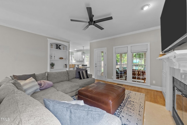 7908 Mayapple Pl, Raleigh, NC 27613 - living area featuring a ceiling fan, crown molding, a glass covered fireplace, and light wood-style floors