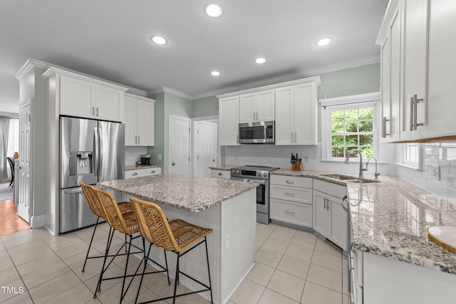 7908 Mayapple Pl, Raleigh, NC 27613 - kitchen featuring appliances with stainless steel finishes, ornamental molding, a kitchen breakfast bar, decorative backsplash, and white cabinets