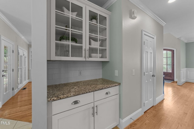 7908 Mayapple Pl, Raleigh, NC 27613 - kitchen with ornamental molding, glass insert cabinets, decorative backsplash, dark stone counters, and white cabinets