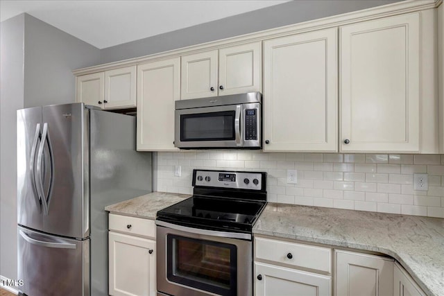 205 Willow Ridge Dr, Louisburg, NC 27549 - kitchen featuring appliances with stainless steel finishes, tasteful backsplash, light stone countertops, and cream cabinets