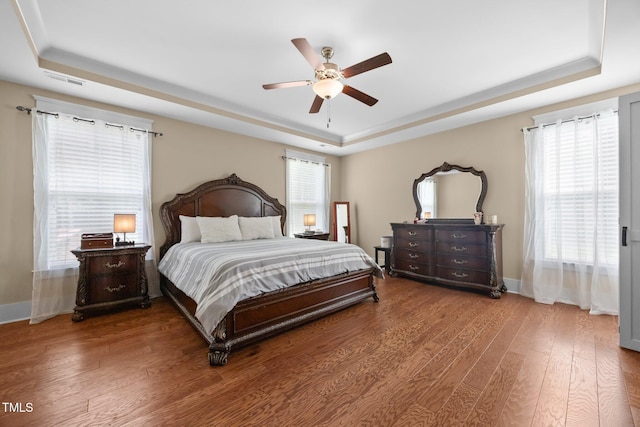 8713 Halsey Ln, Wake Forest, NC 27587 - bedroom featuring a tray ceiling, wood finished floors, multiple windows, and a ceiling fan