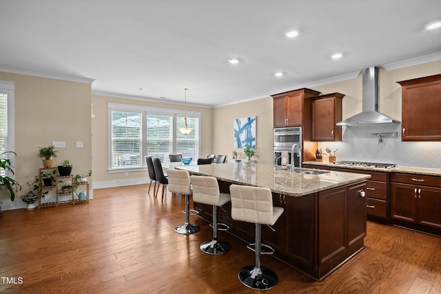 8713 Halsey Ln, Wake Forest, NC 27587 - kitchen featuring wall chimney exhaust hood, crown molding, a breakfast bar area, dark wood finished floors, and light stone countertops