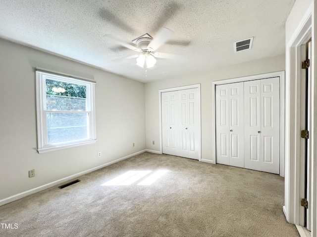 2206 Alpine Rd, Durham, NC 27707 - unfurnished bedroom featuring two closets, carpet, a textured ceiling, and a ceiling fan