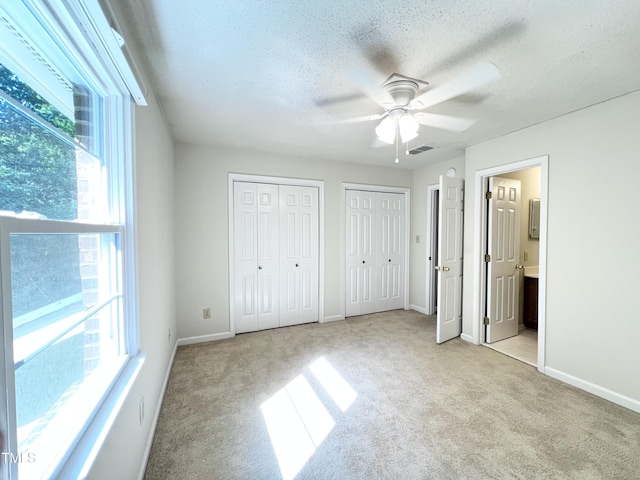 2206 Alpine Rd, Durham, NC 27707 - unfurnished bedroom with light carpet, two closets, a textured ceiling, ensuite bath, and ceiling fan