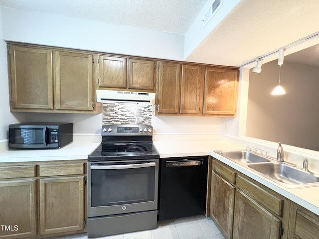 2206 Alpine Rd, Durham, NC 27707 - kitchen with appliances with stainless steel finishes, under cabinet range hood, track lighting, light countertops, and light tile patterned flooring