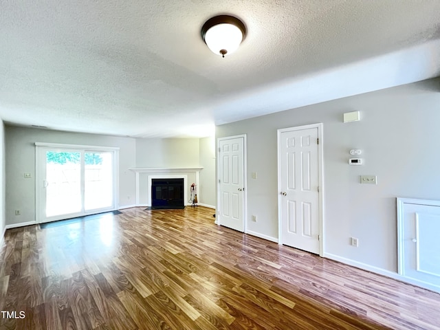 2206 Alpine Rd, Durham, NC 27707 - unfurnished living room featuring a textured ceiling, wood finished floors, and a fireplace with flush hearth