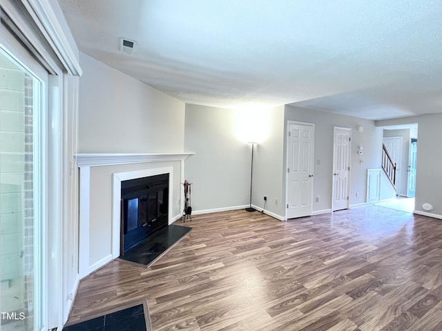2206 Alpine Rd, Durham, NC 27707 - unfurnished living room with wood finished floors, a glass covered fireplace, and stairway