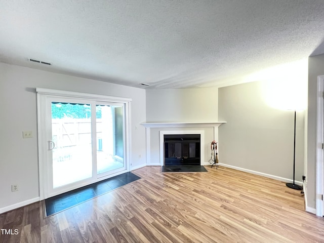 2206 Alpine Rd, Durham, NC 27707 - unfurnished living room with wood finished floors, a textured ceiling, and a fireplace with flush hearth