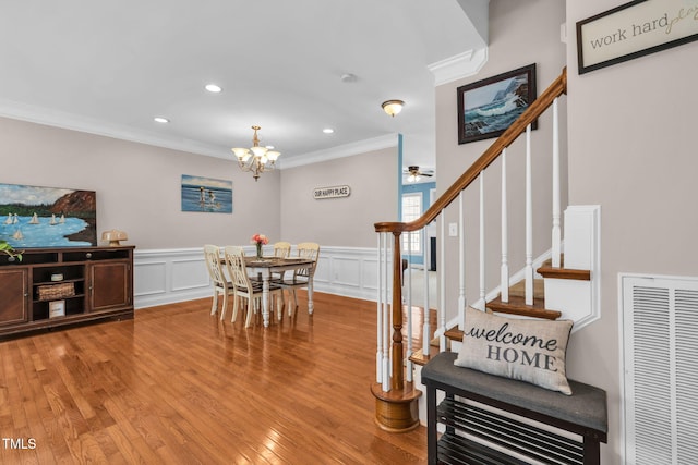 2506 Happy Ln, Raleigh, NC 27614 - dining area with ornamental molding, light wood finished floors, stairway, a chandelier, and wainscoting