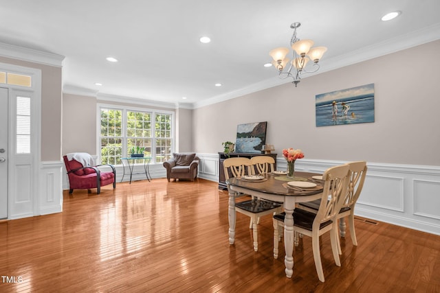 2506 Happy Ln, Raleigh, NC 27614 - dining area with a chandelier, a wainscoted wall, a decorative wall, crown molding, and hardwood / wood-style floors