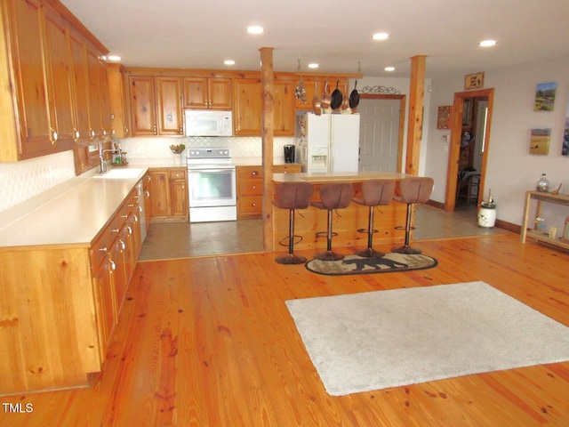 1159 Flemingtown Rd, Henderson, NC 27537 - kitchen with white appliances, light countertops, decorative backsplash, a breakfast bar area, and light wood-type flooring