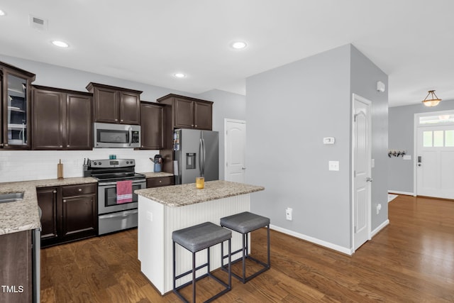 3716 Landshire View Ln, Raleigh, NC 27616 - kitchen with appliances with stainless steel finishes, dark brown cabinetry, a kitchen island, backsplash, and dark wood-type flooring