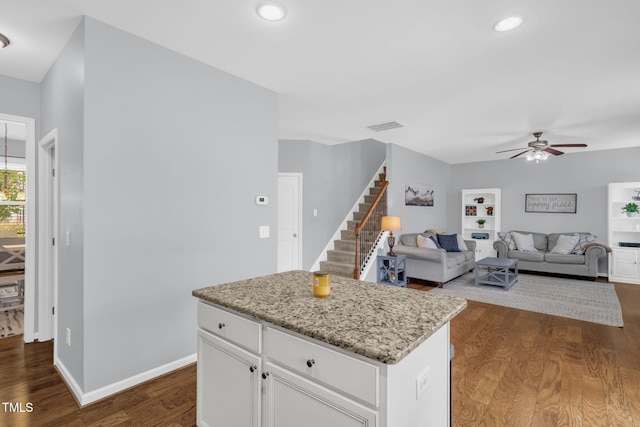 3716 Landshire View Ln, Raleigh, NC 27616 - kitchen with ceiling fan, dark wood finished floors, white cabinetry, a kitchen island, and light stone counters