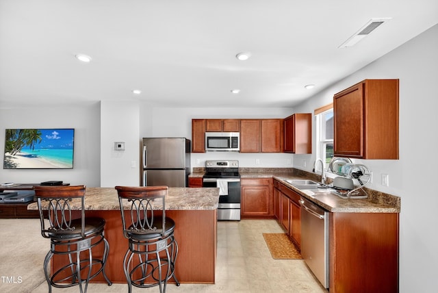 3 Windchime Ct, Durham, NC 27704 - kitchen featuring stainless steel appliances, a kitchen bar, a kitchen island, recessed lighting, and brown cabinets