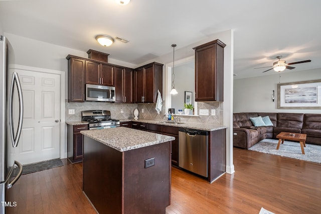 701 Laurel Spring Dr, Fuquay Varina, NC 27526 - kitchen featuring appliances with stainless steel finishes, open floor plan, dark brown cabinetry, dark wood-style floors, and decorative backsplash