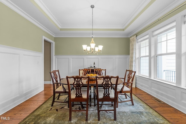 5005 Clyden Cv, Raleigh, NC 27612 - dining room with a decorative wall, a tray ceiling, a chandelier, crown molding, and wood finished floors
