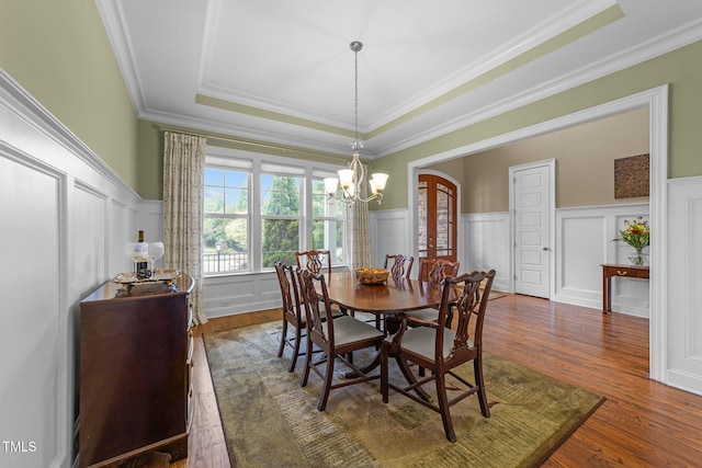 5005 Clyden Cv, Raleigh, NC 27612 - dining space with a decorative wall, a tray ceiling, wood finished floors, a chandelier, and ornamental molding