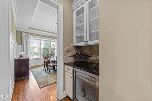 5005 Clyden Cv, Raleigh, NC 27612 - indoor dry bar featuring beverage cooler, wood finished floors, backsplash, ornamental molding, and a raised ceiling