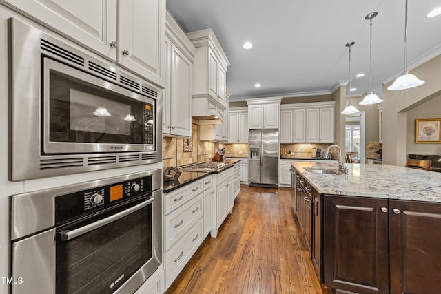 5005 Clyden Cv, Raleigh, NC 27612 - kitchen featuring appliances with stainless steel finishes, crown molding, dark brown cabinetry, white cabinetry, and dark wood finished floors