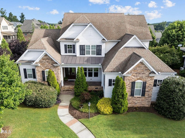 5005 Clyden Cv, Raleigh, NC 27612 - craftsman-style home with stone siding, roof with shingles, a front yard, and a porch