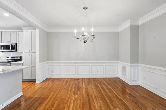 306 Kirkeenan Cir, Morrisville, NC 27560 - unfurnished dining area featuring a chandelier, crown molding, wood finished floors, a wainscoted wall, and recessed lighting