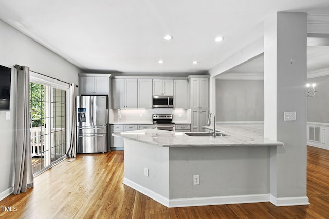 306 Kirkeenan Cir, Morrisville, NC 27560 - kitchen with stainless steel appliances, light stone countertops, a peninsula, light wood-style floors, and crown molding