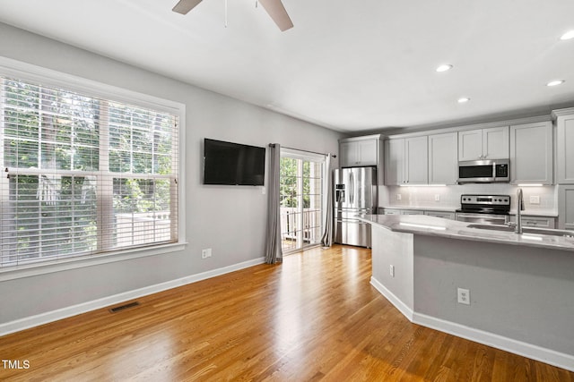306 Kirkeenan Cir, Morrisville, NC 27560 - kitchen with appliances with stainless steel finishes, a ceiling fan, light wood-style flooring, recessed lighting, and light stone countertops