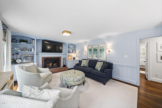 809 Blenheim Dr, Raleigh, NC 27612 - living area featuring dark wood-style floors, crown molding, a fireplace, built in shelves, and wainscoting