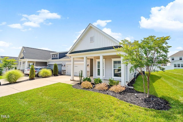 6531 Knob Creek Dr, Whitsett, NC 27377 - view of front of house with board and batten siding, concrete driveway, a front yard, an attached garage, and a porch