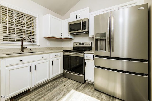 190 Hardwood Dr, Franklinton, NC 27525 - kitchen with stainless steel appliances, lofted ceiling, white cabinetry, light countertops, and light wood-type flooring