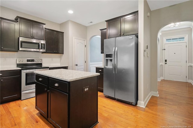 1234 Micahs Way N, Spring Lake, NC 28390 - kitchen with appliances with stainless steel finishes, arched walkways, a center island, light wood-style floors, and decorative backsplash