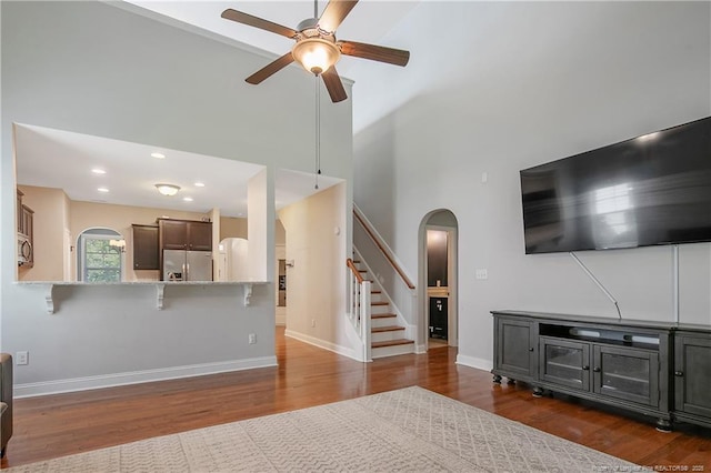 1234 Micahs Way N, Spring Lake, NC 28390 - living area with arched walkways, ceiling fan, a towering ceiling, wood finished floors, and stairs