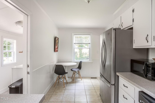 2331 Stevens Rd, Raleigh, NC 27610 - kitchen with black microwave, light countertops, white cabinets, a wainscoted wall, and light tile patterned floors