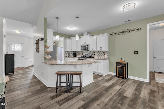 450 Cotton Mill Dr, Zebulon, NC 27597 - kitchen with stainless steel appliances, a breakfast bar area, dark wood-style flooring, decorative backsplash, and a peninsula