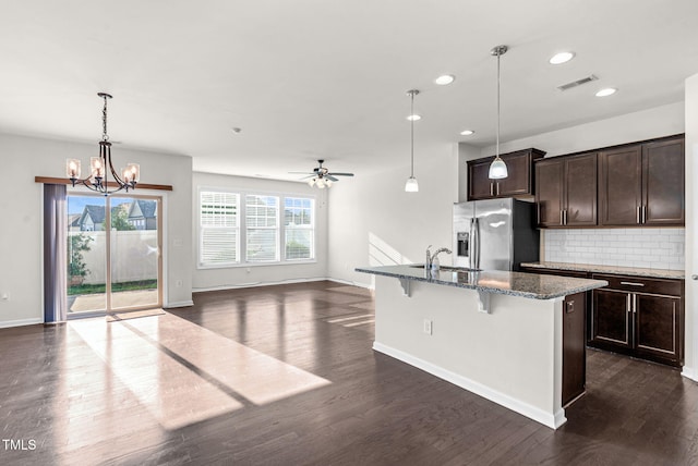 7817 Elmshire Way, Raleigh, NC 27616 - kitchen with stainless steel refrigerator with ice dispenser, dark stone countertops, dark wood-style floors, a breakfast bar area, and tasteful backsplash